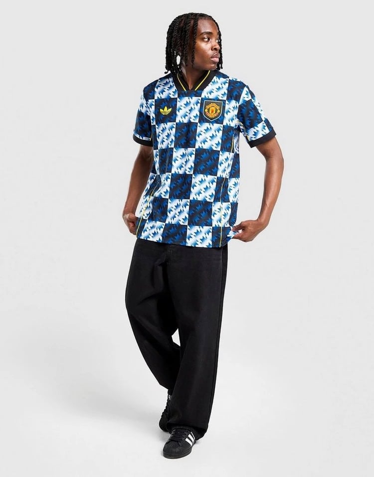 jd_760195_e | AE JERSEY Person wearing a blue-and-white checker-pattern football jersey with team crest, black wide-leg pants, and black sneakers, posing in a studio.