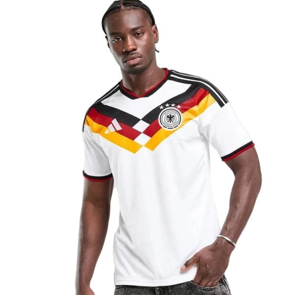Male model wearing a white Germany national team soccer jersey with black, red, and gold chevron across the chest.