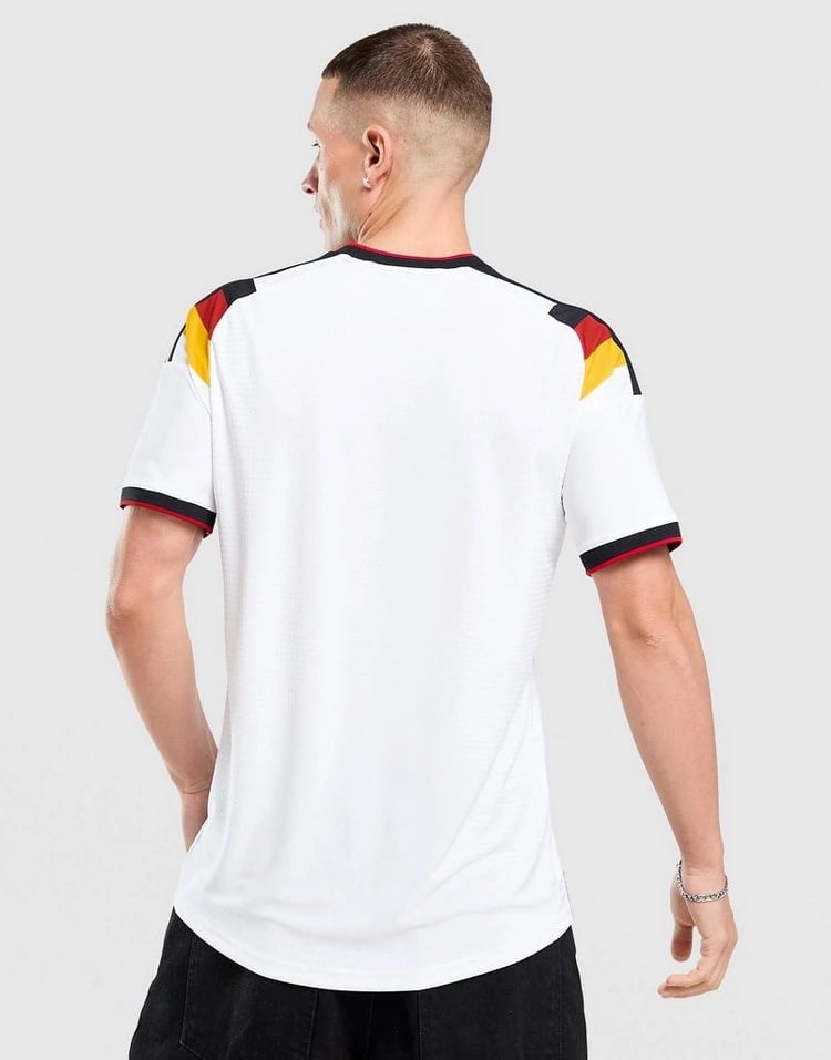 jd_776182_c | AE JERSEY Back view of a man wearing a white football jersey with black, red, and yellow shoulder accents on the sleeves and collar edge.