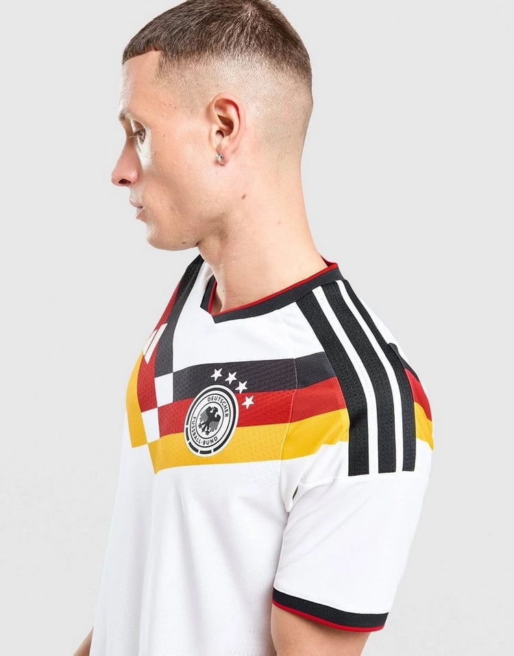 jd_776182_d | AE JERSEY Side profile of a man in a white Germany national team jersey with black, red, and gold stripes and crest on the chest markups the Adidas design.