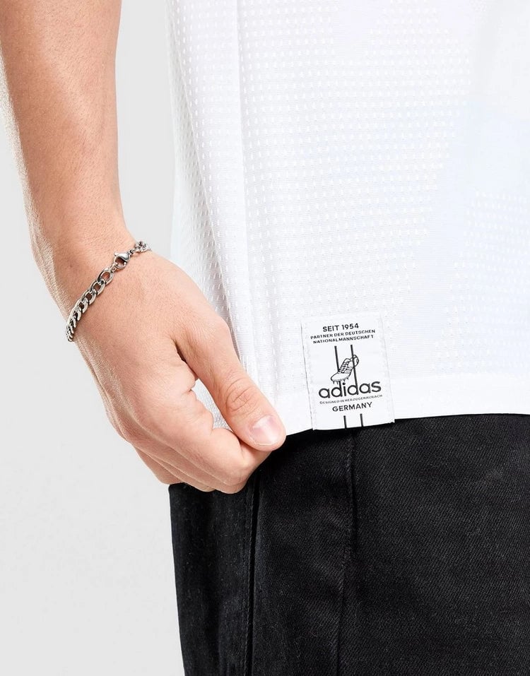 jd_776182_f | AE JERSEY Close-up of a white Adidas jersey hem with a visible brand label and a metal bracelet on the wrist.