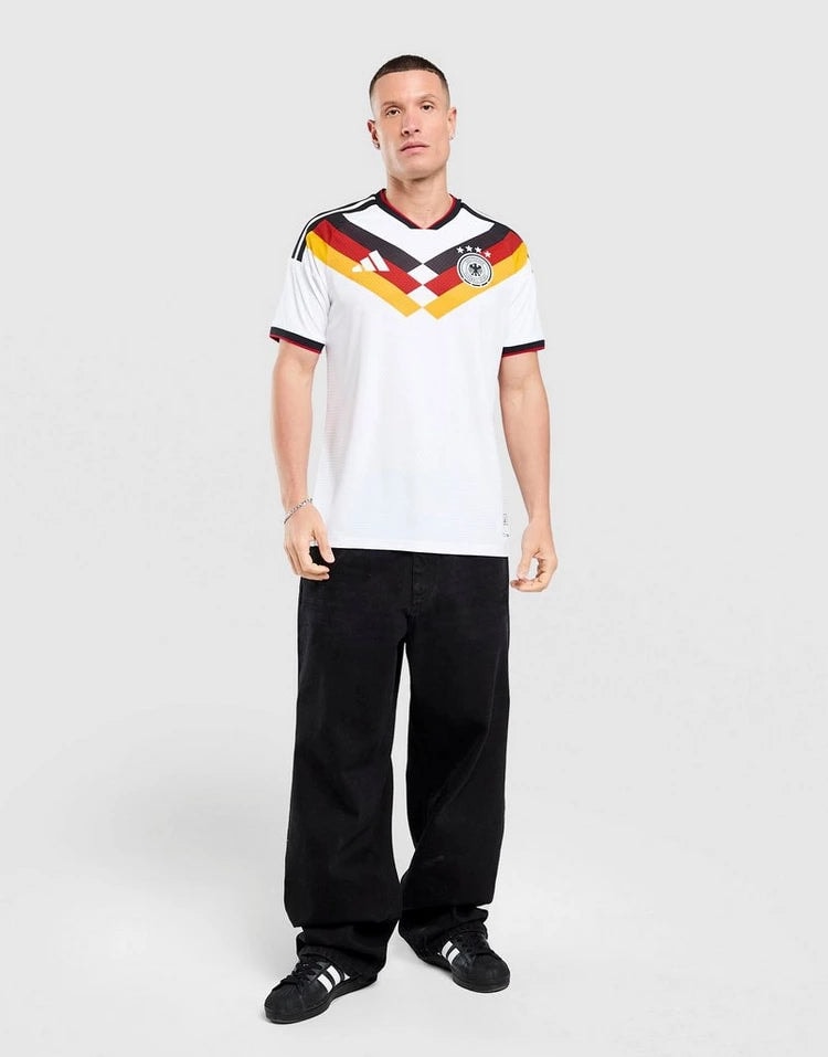 jd_776182_g | AE JERSEY Man wearing a white Germany national football team jersey with black jeans and sneakers, standing in a neutral studio background.