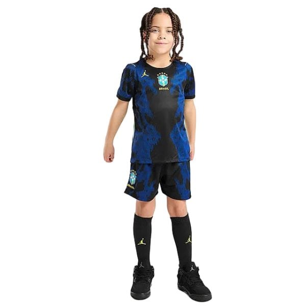 Young child wearing Brazil national team soccer kit—a blue and black patterned jersey with crest, matching shorts, and black socks, facing the camera.