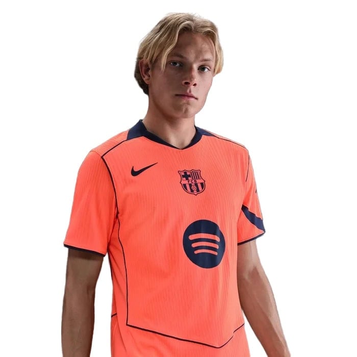 ku | AE JERSEY Young man wearing a neon orange FC Barcelona football jersey with the Spotify sponsor logo on the chest and a Nike swoosh nearby