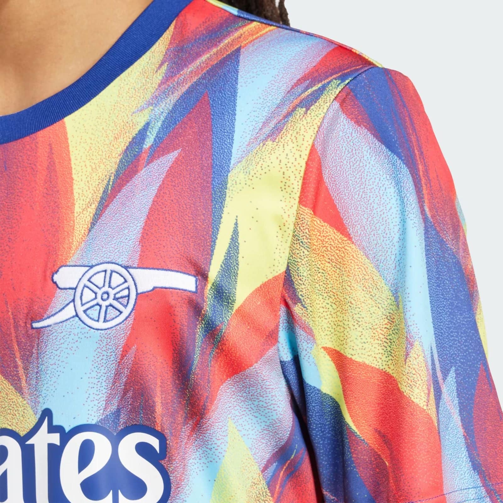 l0IjlvG2gAGRURa | AE JERSEY Close-up of a vibrant, multicolored sports jersey with an Arsenal cannon crest visible on the chest area.