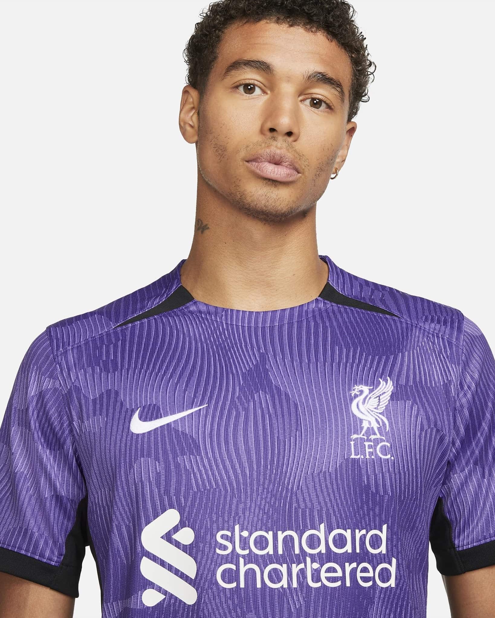 liverpool-third-jersey-202324-333525_8311464c-360b-43da-a4b8-c54b56393471 | AE JERSEY Close-up of a person wearing a purple Liverpool FC training jersey with the Standard Chartered logo on the chest