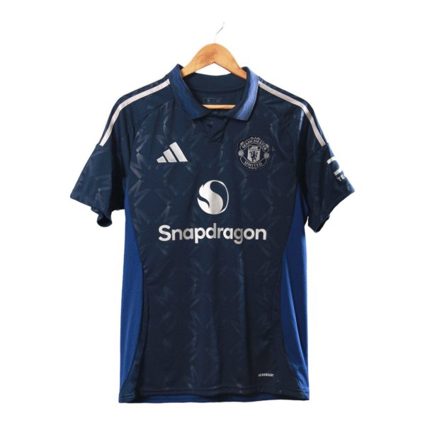 Dark blue Manchester United soccer jersey on a wooden hanger, featuring Adidas logo and Snapdragon sponsor text on front.