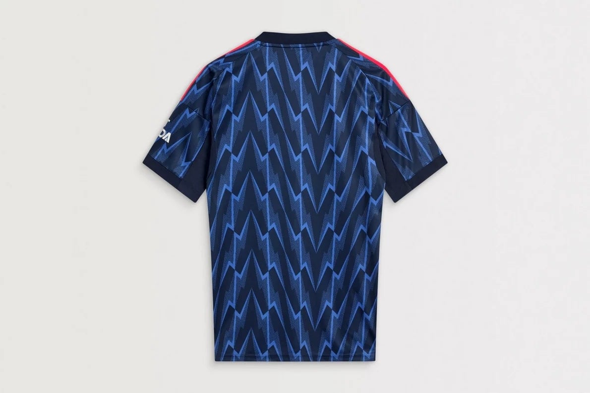 mji9511_b1 | AE JERSEY Back view of a blue zigzag-patterned sports jersey with dark sleeves and red shoulder stripes.