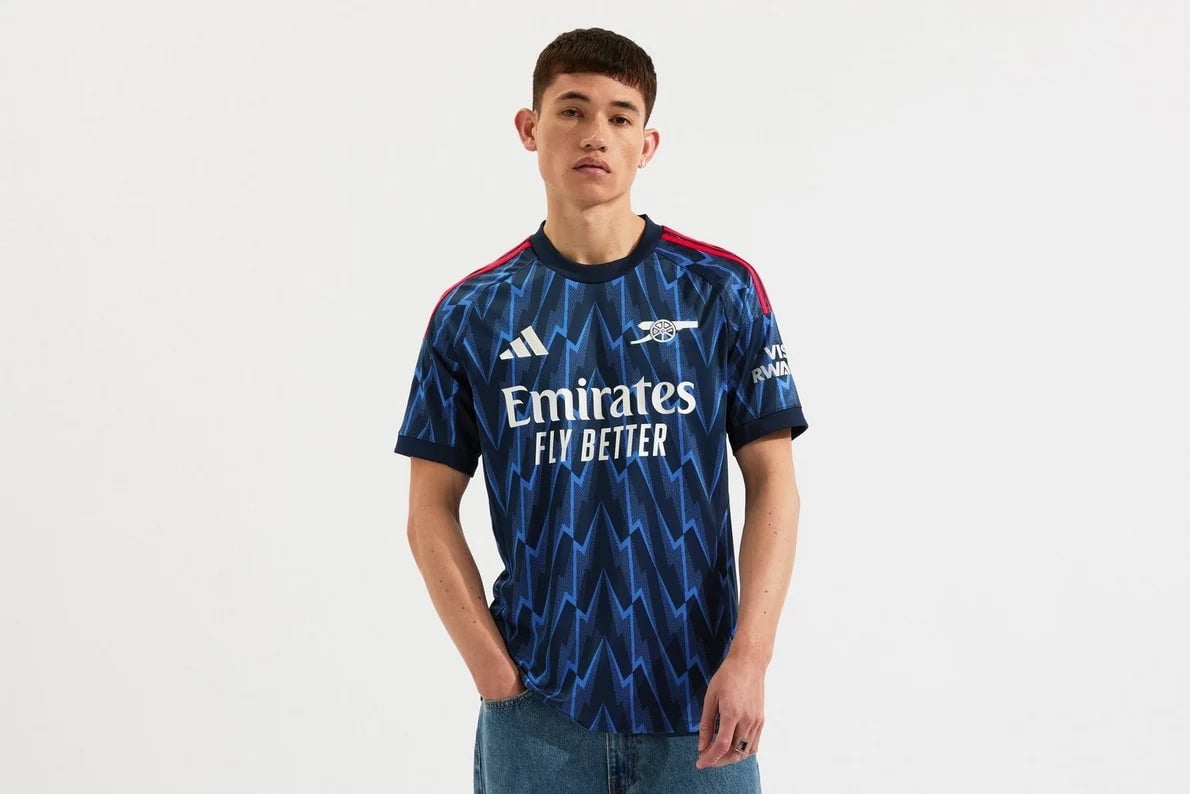 mji9511_f_1 | AE JERSEY Male model wearing Arsenal away jersey in blue zigzag pattern with Emirates Fly Better slogan across the chest.
