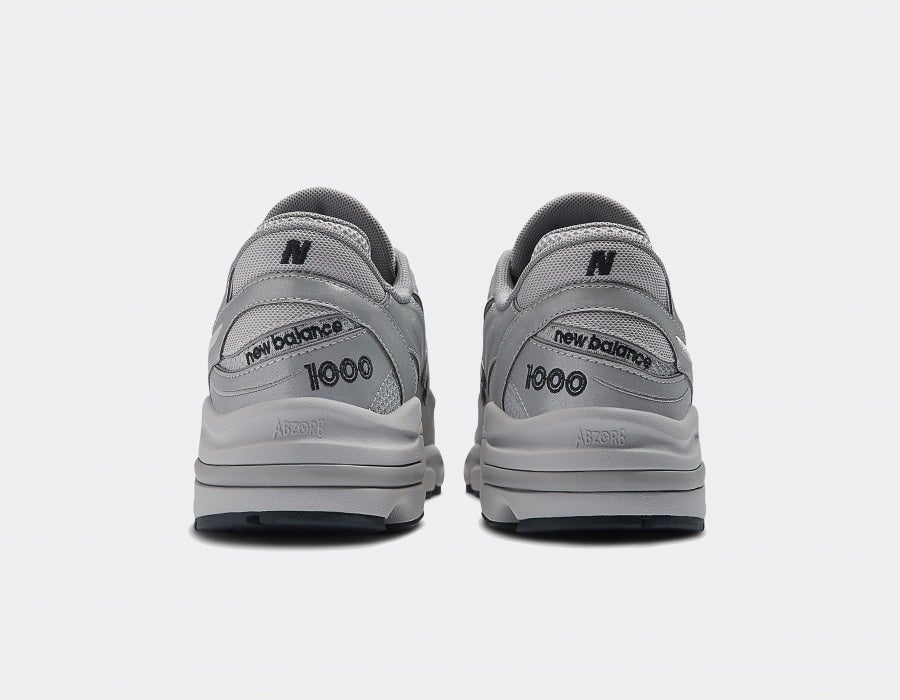 new-balance-m1000-te-reflective-pack-silver_6 | AE JERSEY Pair of gray New Balance sneakers viewed from the back showcasing 'new balance' and '1000' on the heel.
