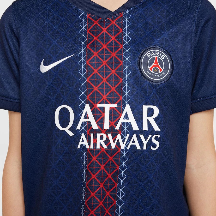 psg-nike-home-stadium-mini-kit-2025-26-little-kids_ss5_p-202333095_pv-7_u-tyikwztu12vnmbnhmwz8_v-qhvmwfbh79ypsspxfarz | AE JERSEY Front view of a PSG soccer jersey featuring the Nike swoosh, crest, and Qatar Airways sponsor on a dark blue kit with red and light blue vertical pattern.