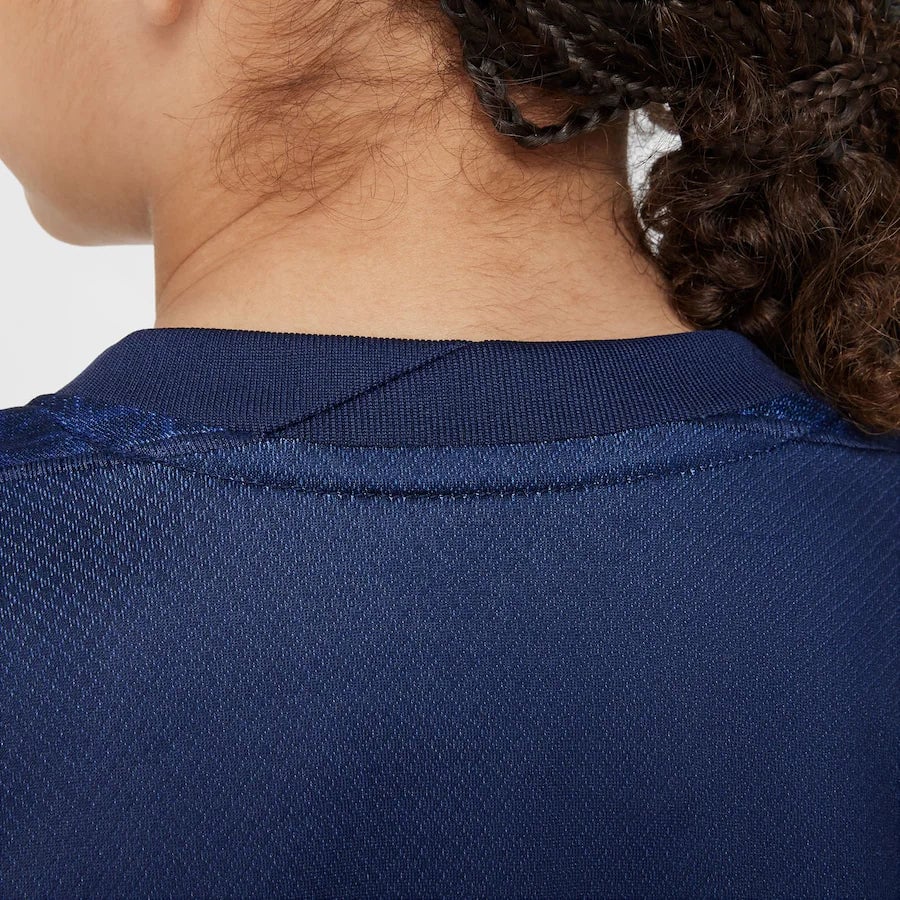 psg-nike-home-stadium-mini-kit-2025-26-little-kids_ss5_p-202333095_pv-9_u-tyikwztu12vnmbnhmwz8_v-fqikdrrb06vr5it7acvp | AE JERSEY Close-up of the back of a person wearing a dark blue polo shirt, focusing on the collar and upper back.