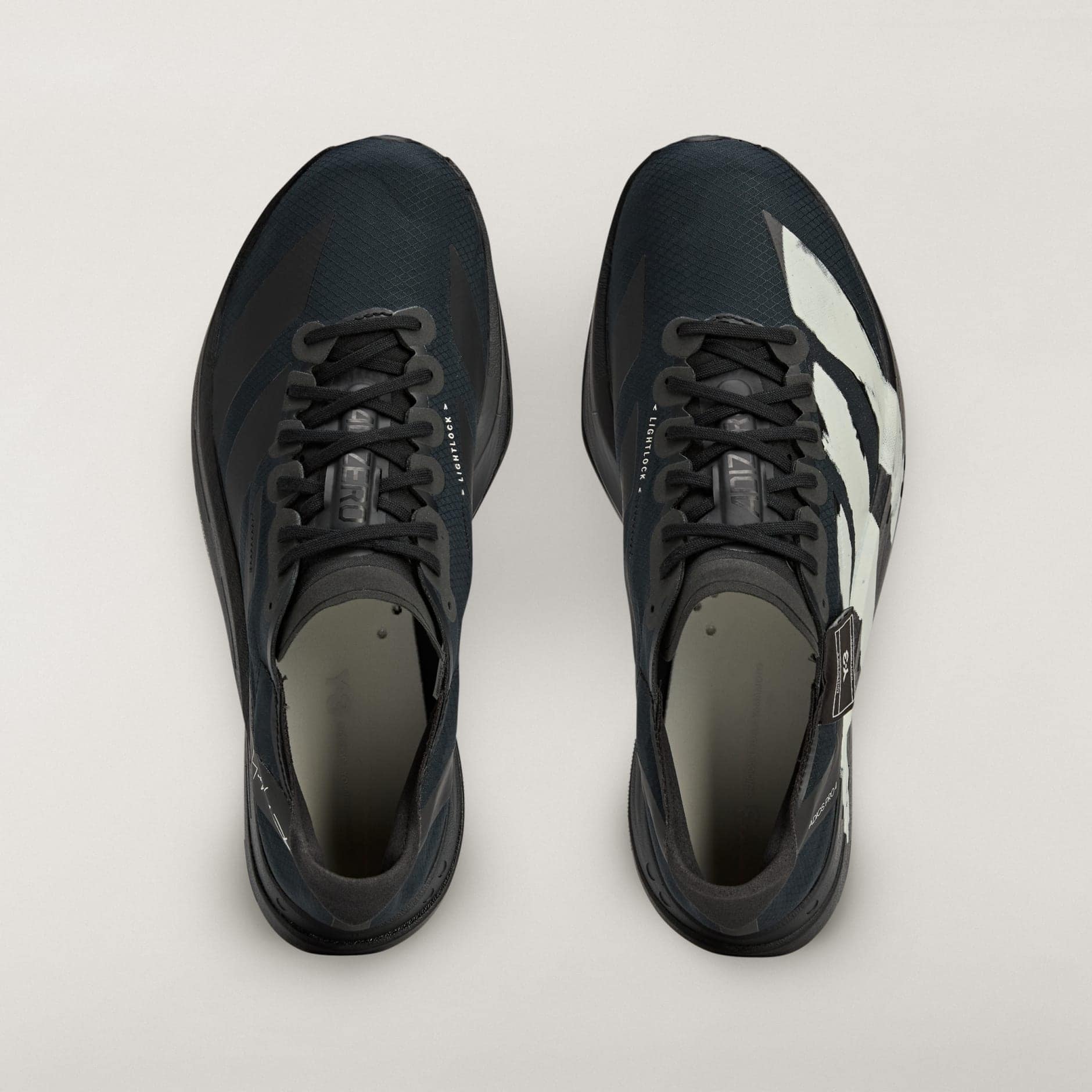 rn-image_picker_lib_temp_1ebde3ca-7fa9-41d0-8f9f-2349b193a39d | AE JERSEY Top-down view of two dark athletic sneakers side by side on a pale background, viewed from above.