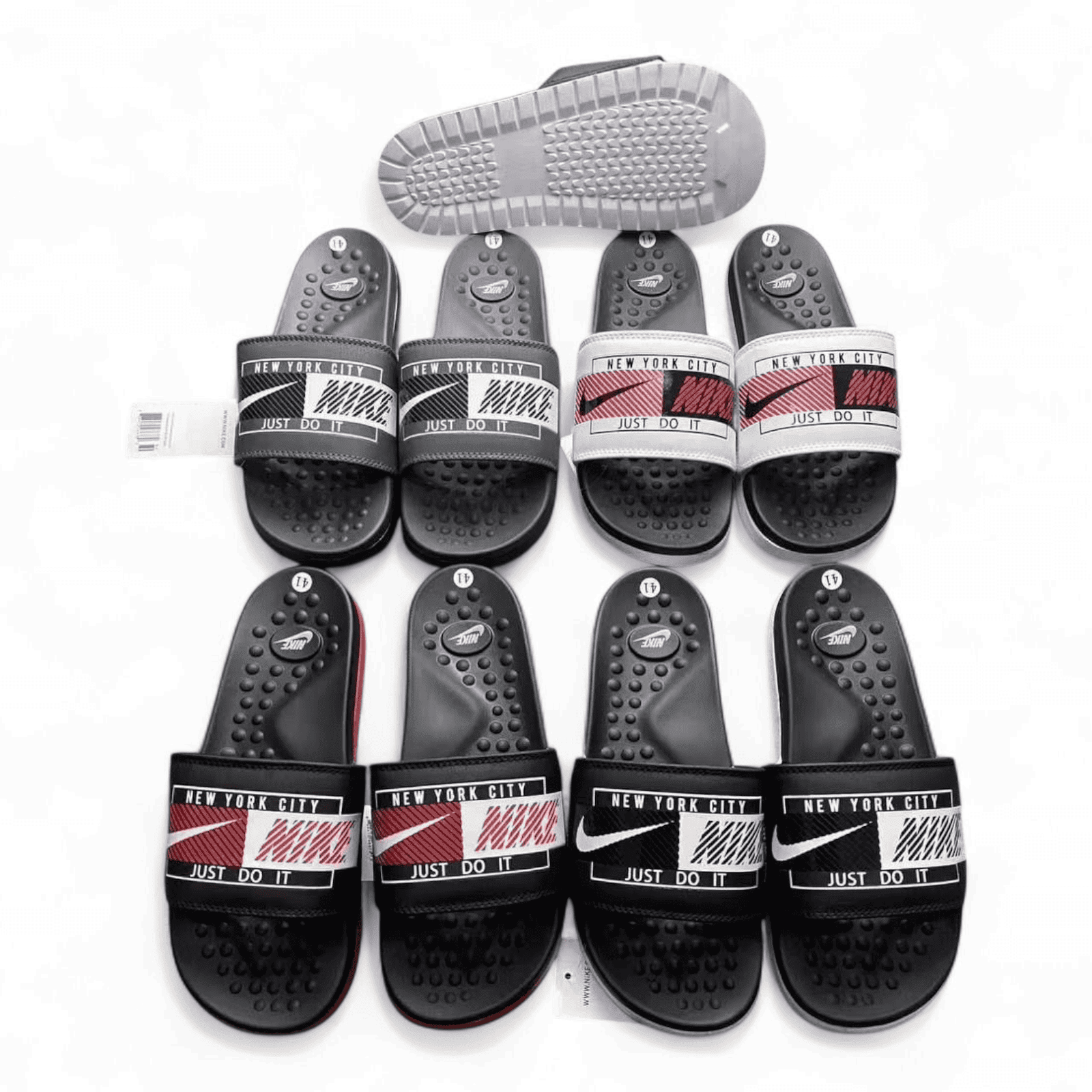 rn-image_picker_lib_temp_29014ec2-e578-4096-91c7-276365728320 | AE JERSEY Row of black Nike slide sandals with 'New York City' and 'Just Do It' straps on a white background.