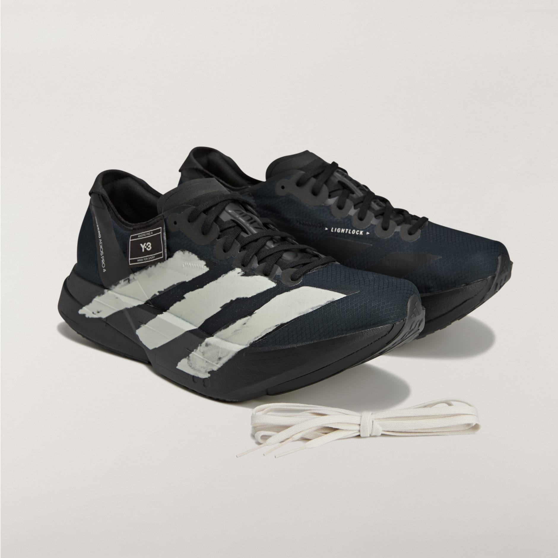 rn-image_picker_lib_temp_4ae8792a-394f-4e07-b7a7-1cc3729c42f9 | AE JERSEY Black Adidas running shoes with white stripes on a light background, white laces nearby.