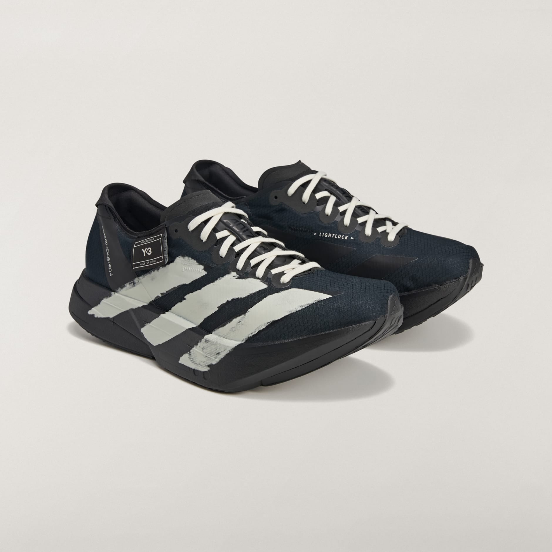 rn-image_picker_lib_temp_5e48eb59-a9ba-45af-8e3c-03f7b3b0be1e | AE JERSEY Close-up of black athletic shoes with white stripes against a light background, showing side details and laces.