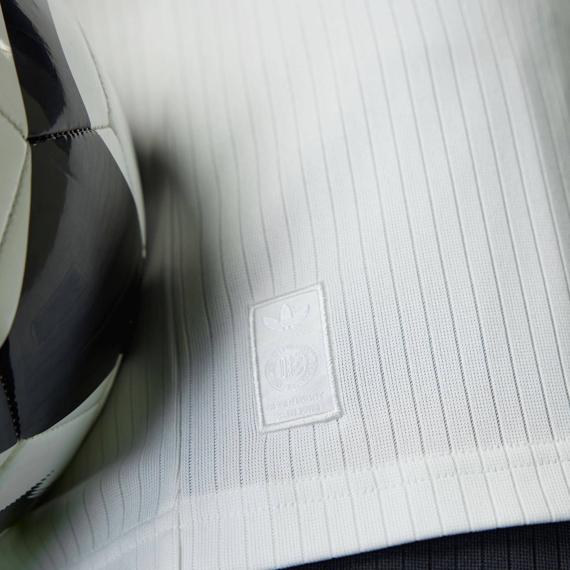 rn-image_picker_lib_temp_6231cdbc-b134-4f2f-9c4b-95c00f10d206 | AE JERSEY Close-up of light gray car seat fabric with a stitched Adidas badge.