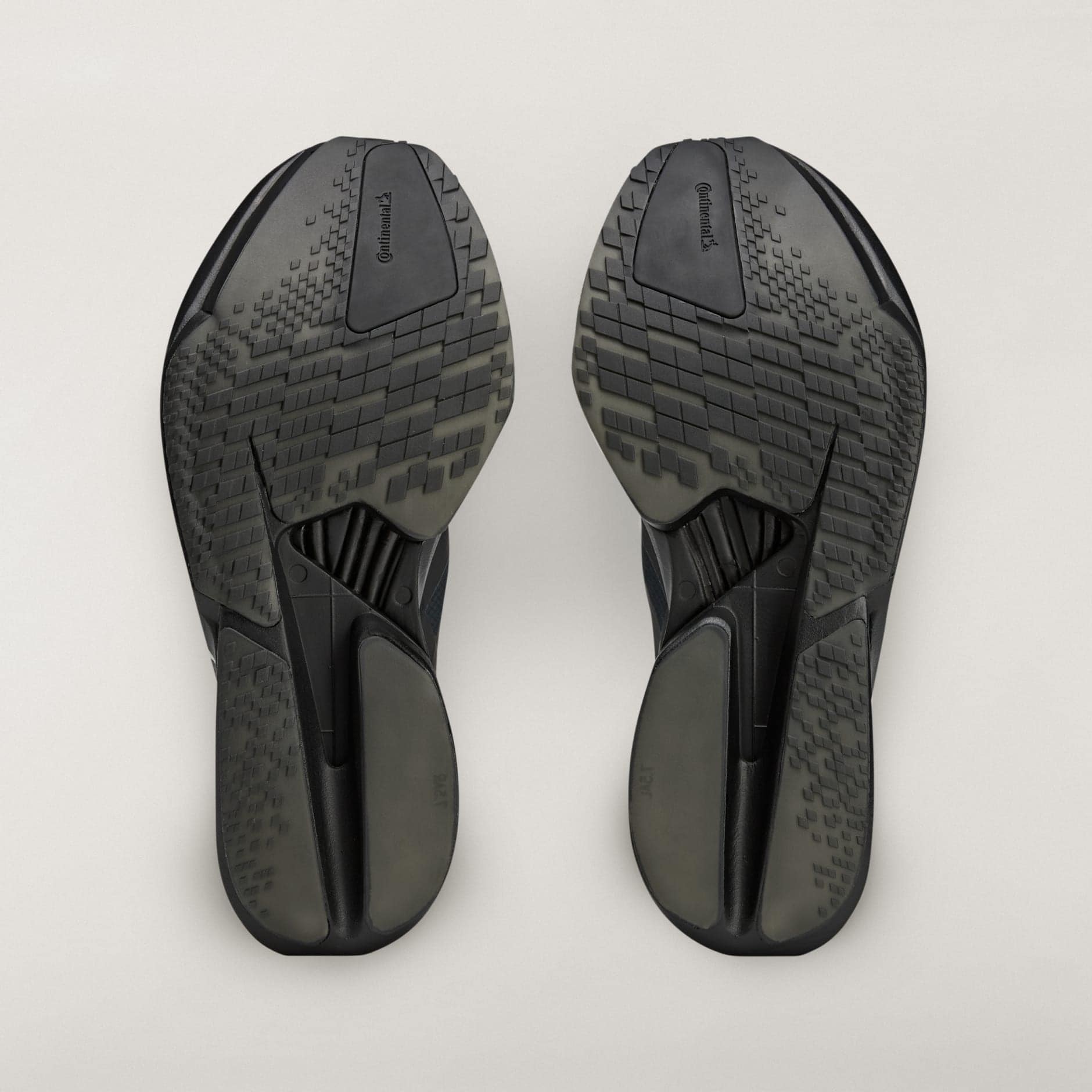 rn-image_picker_lib_temp_65f25bd4-d280-402d-8c14-58083bc5f58d | AE JERSEY Bottom view of two dark sneakers with textured sole patterns facing upward