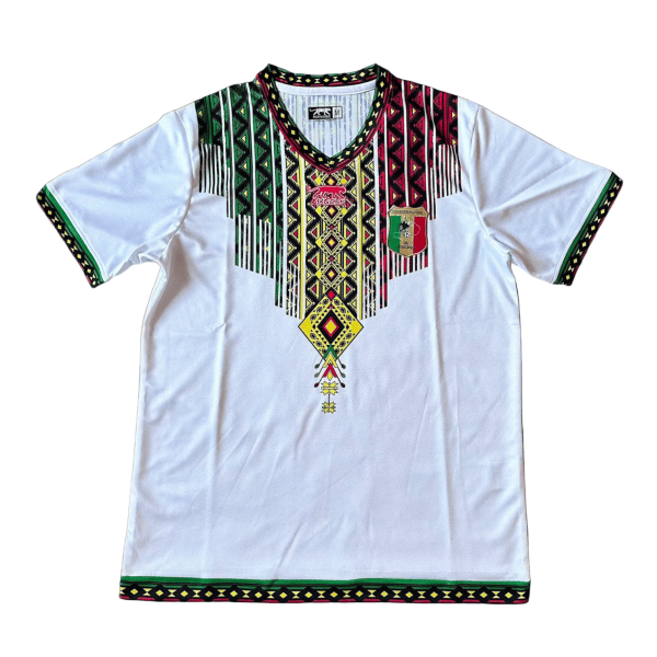 White dashiki-style tunic with multicolor geometric embroidery around the V-neck and sleeves, white body, and a shield emblem on the left chest.