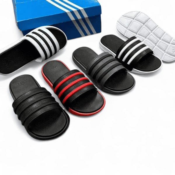 Assorted black and red striped slide sandals arranged with a blue shoebox on a white background