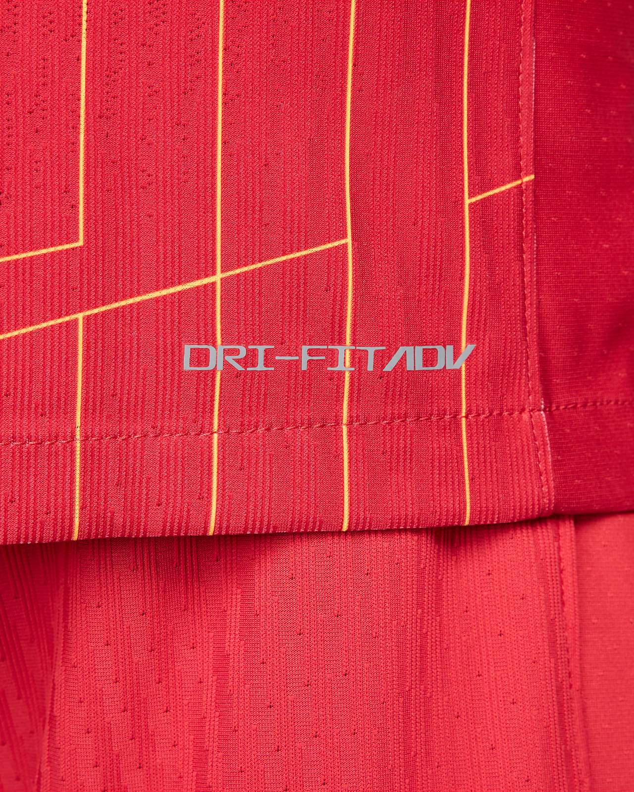 rn-image_picker_lib_temp_ad097d27-c1fe-4325-aa69-b717074c067b | AE JERSEY Close-up of red athletic fabric with vertical yellow piping and the DRI-FIT ADV logo visible.