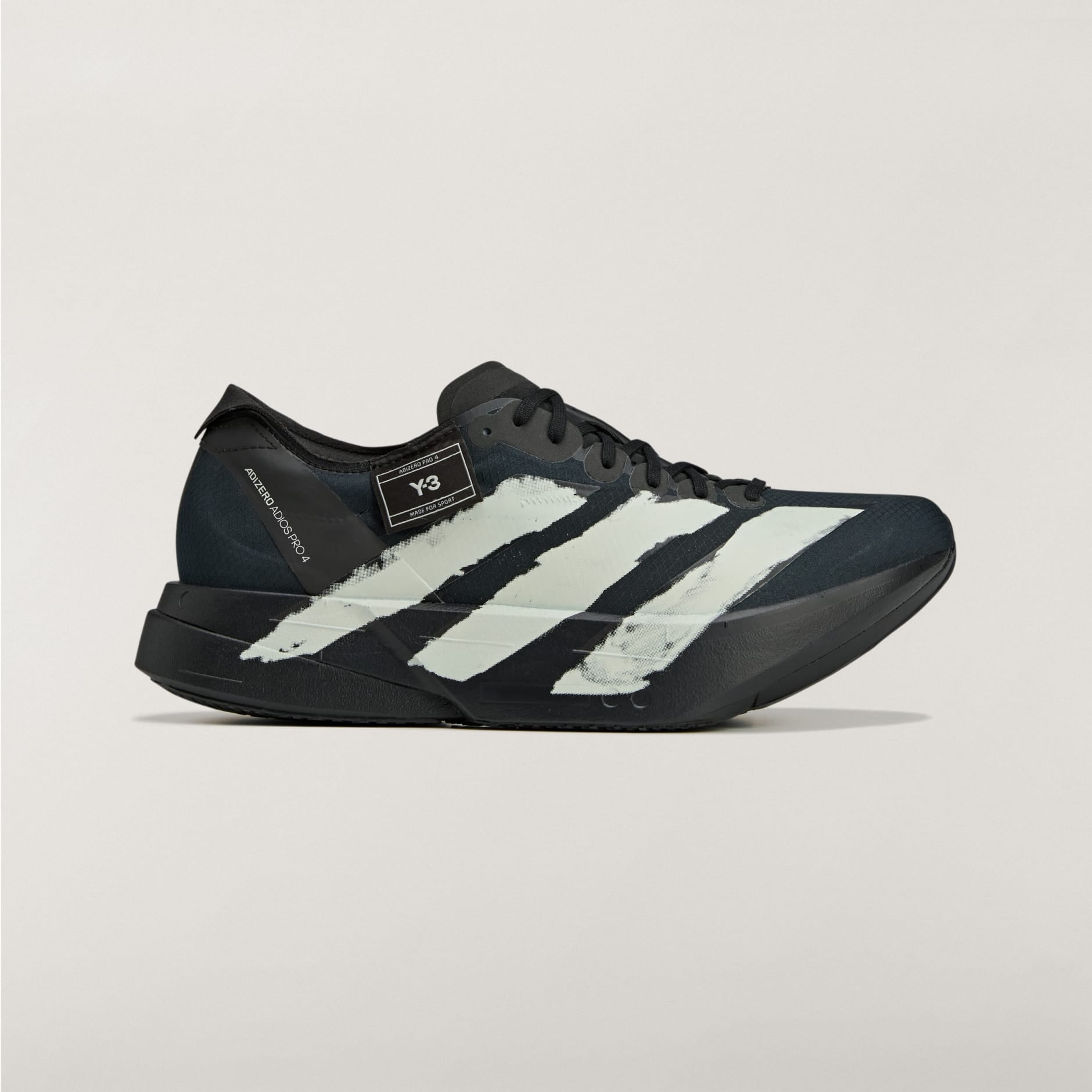 rn-image_picker_lib_temp_cc337175-fc19-4f8d-a895-3511192cc56a | AE JERSEY Close-up of a black Adidas sneaker with white stripes on a pale background, showing the toe and laces area.
