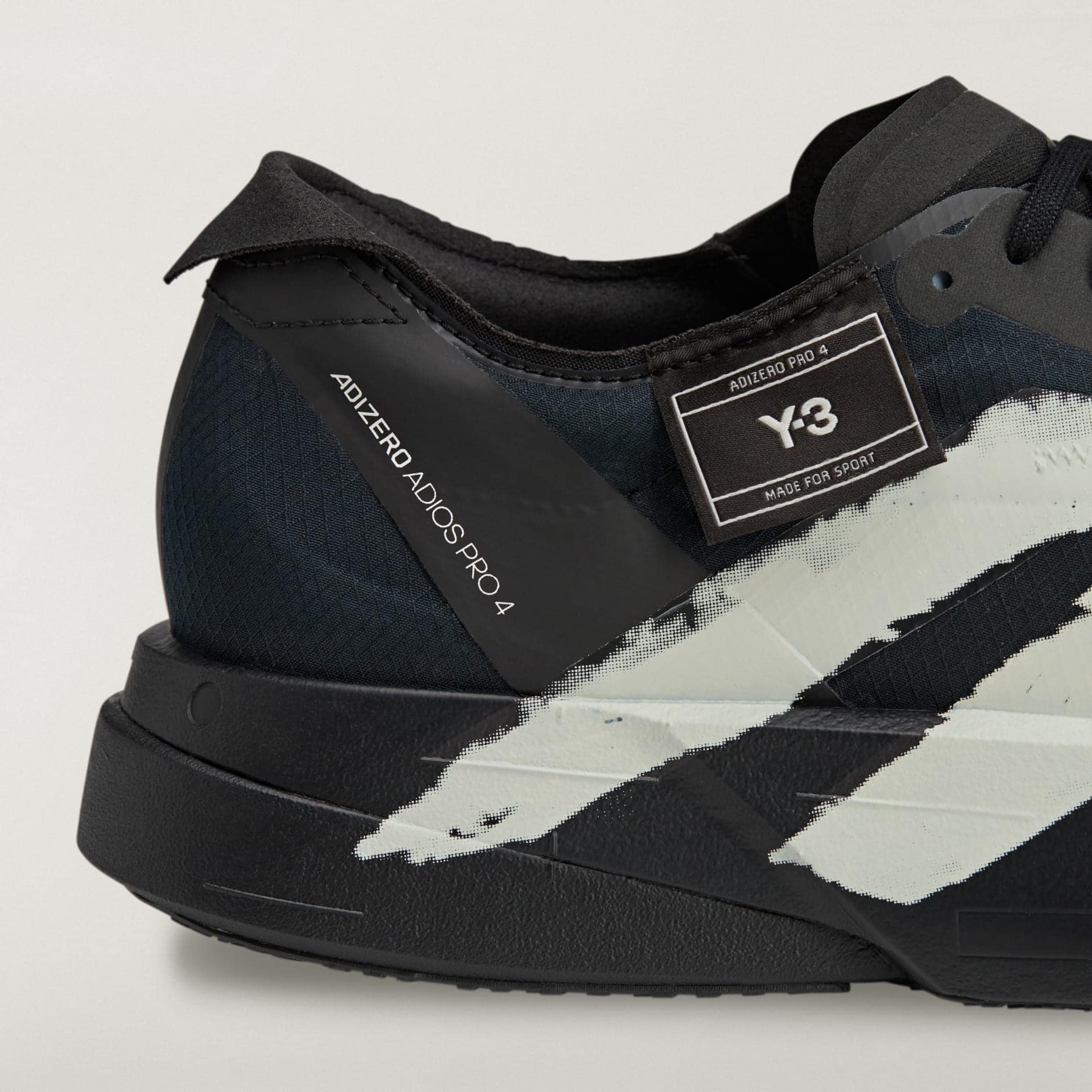 rn-image_picker_lib_temp_d74d390b-bae1-4b66-bfa2-7e6812841a7d | AE JERSEY Close-up of a black sneaker showing a textured upper, stitched details, and a Velcro strap with a label reading Y-3 Adidas Pro 4.