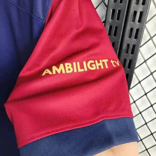 rn-image_picker_lib_temp_e2b5901d-09e3-46b1-b7e1-a5eae79299d0 | AE JERSEY Red sleeve with yellow AMBILIGHT tv logo on a navy cuff against a metal rack background