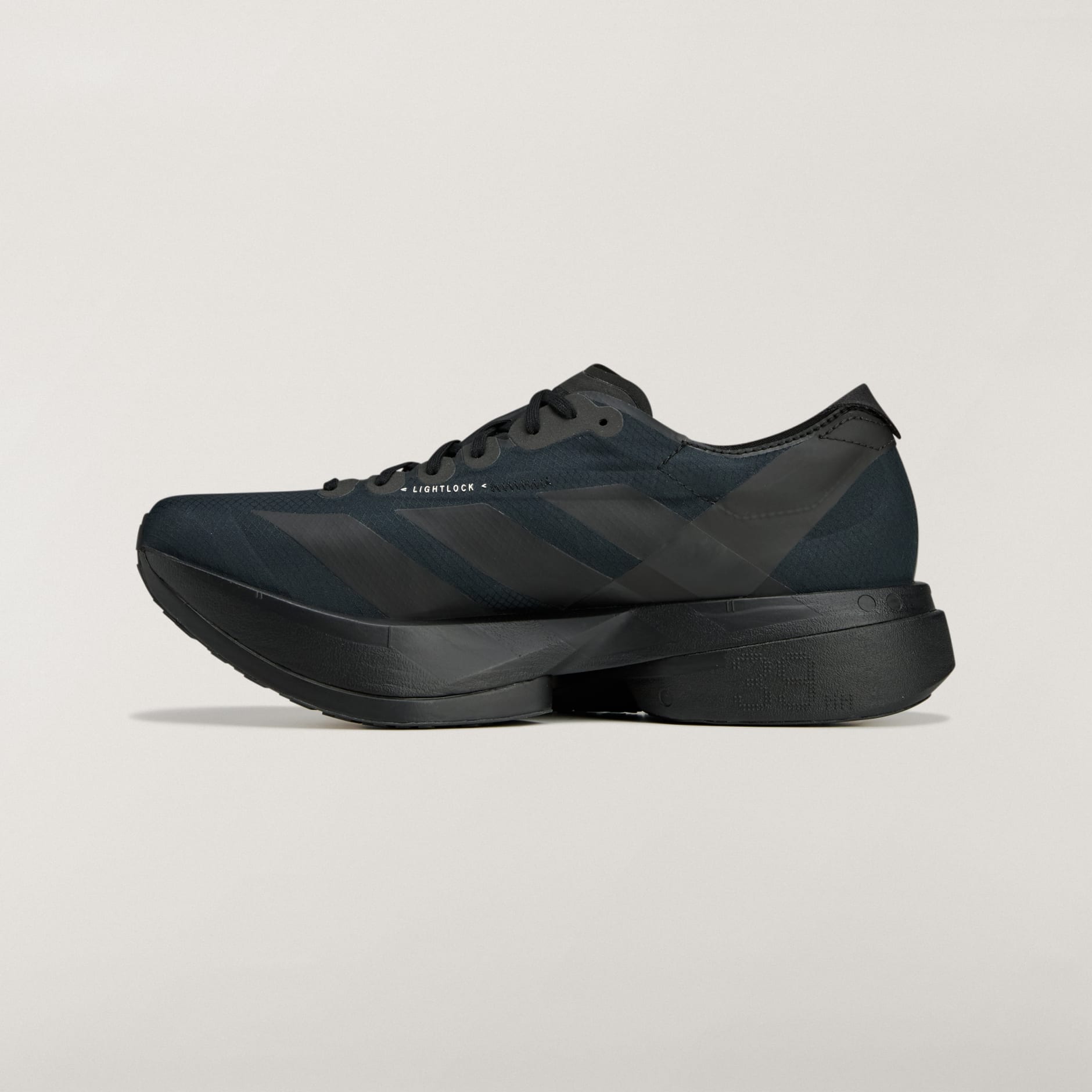 rn-image_picker_lib_temp_edd710ba-c067-4c30-8169-d14b65dec7dd | AE JERSEY Dark black athletic shoe shown from a low side angle, featuring a thick platform sole and 'LIGHTLOCK' branding on the midsection