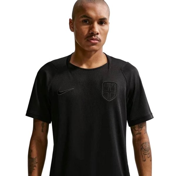 Portrait of a man wearing a black Nike t-shirt with a shield crest, facing the camera against a plain background.