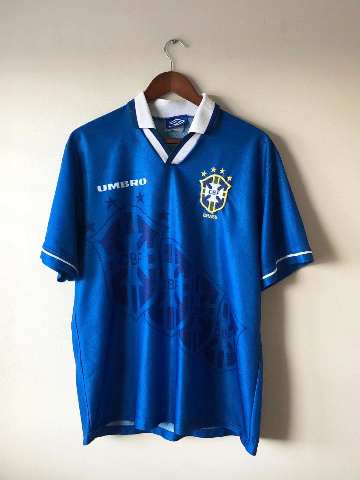 s-l1600_49cacafc-e97f-4cdb-9650-f52d781e62c0 | AE JERSEY Blue Brazil national team soccer jersey on a wooden hanger, featuring the Umbro logo and CBF crest on the chest.