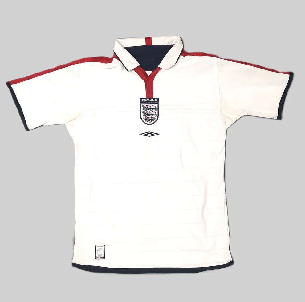 White England national football team jersey with red trim and team crest on the chest, by Umbro, on a gray background